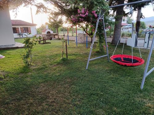 a playground with a red swing in a yard at Cozy Garden House in Árgos Orestikón