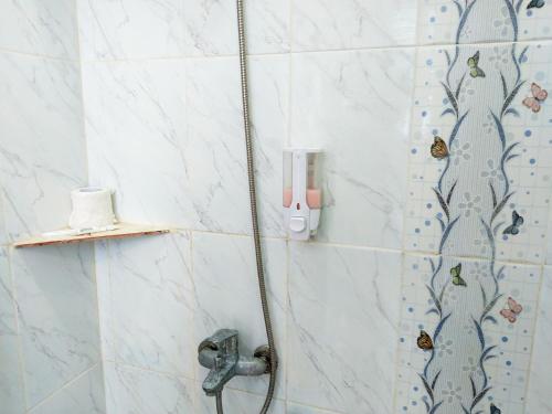 a shower in a bathroom with butterflies on the wall at Themas Guest House in Jakarta