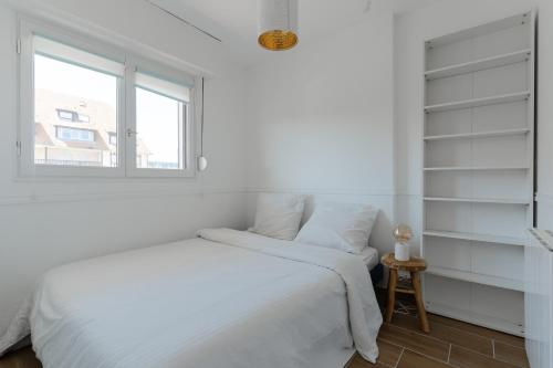 une chambre blanche avec un lit et une fenêtre dans l'établissement Le Cosy du Grand Cap - Appt avec balcon vue mer, à Villers-sur-Mer