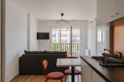 une cuisine et un salon avec un canapé et une table dans l'établissement Le Cosy du Grand Cap - Appt avec balcon vue mer, à Villers-sur-Mer