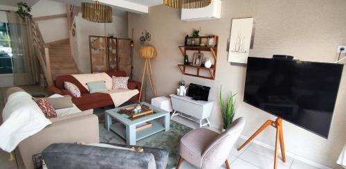 a living room with a large flat screen tv at Maison d'Hestia, charme, piscine, proche du bord de mer et de Royan in Arces-sur-Gironde