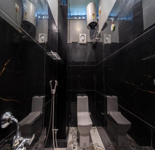 a black bathroom with a toilet and a sink at Hotel Bees in Puducherry