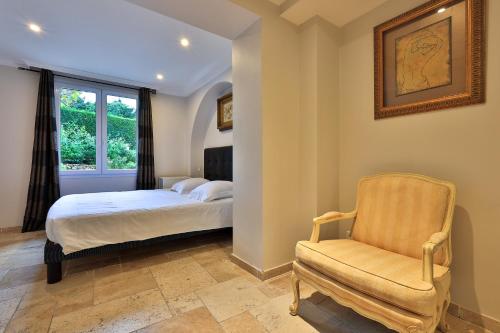 a bedroom with a bed and a chair and a window at Emeraude Résidence Hotelière in Juan-les-Pins