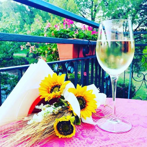 a glass of wine and a bunch of sunflowers on a table at I Fiori di Margherita Luxury B&B in Perugia