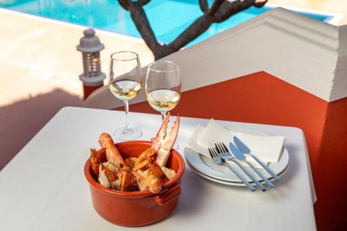 a table with a bowl of shrimp and two glasses of wine at Belavista Da Luz - Wellness & Lifestyle Hotel in Luz