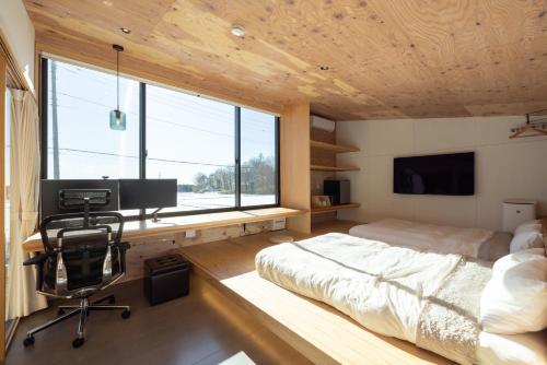 a bedroom with a bed and a desk with a computer at 森deワーケなすっぽ 木の温もりとホテルライクな佇まい 森のバレルサウナ in Nasu-yumoto