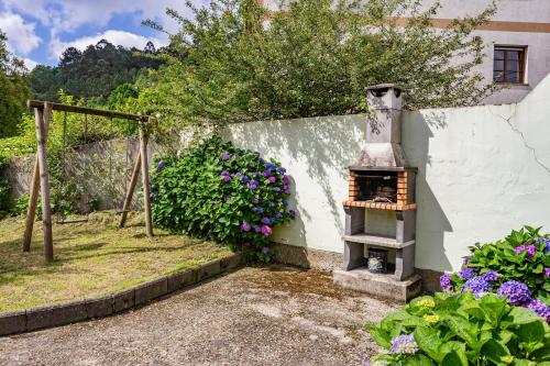 a outdoor oven in a garden with flowers at Maseda 2 in Villayón
