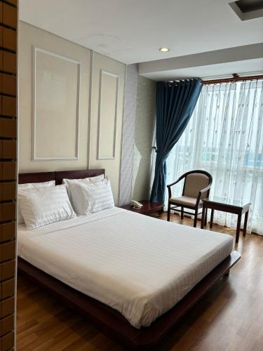 a bedroom with a bed and a chair and a window at Kim Tho Hotel in Can Tho