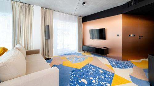 a living room with a couch and a flat screen tv at Aparthotel Biała Perła - Czarna Góra Resort, Sun & Snow in Sienna
