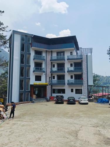 a large building with cars parked in front of it at Hotel Sudesh Ganga in Sonprayag