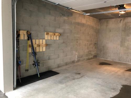 un garage vide avec un mur de briques et des outils dans l'établissement VAUJANYLOCATIONS - Amethystes B3, à Vaujany
