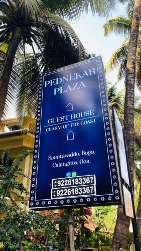 a blue sign in front of a building with palm trees at Pednekar Plaza Inn in Baga