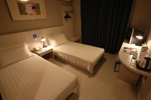 西寧市にあるJinjiang Inn Xining Mojia Street Food Streetのベッド2台とデスクが備わる小さなホテルルームです。