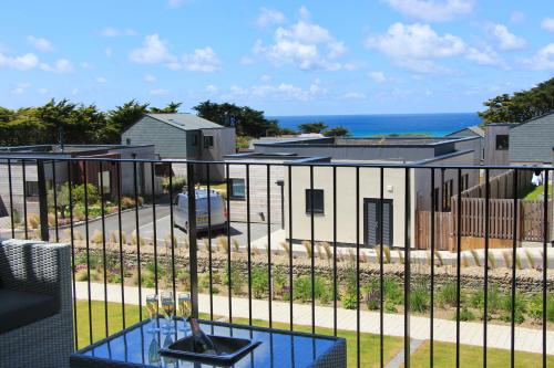 a balcony with a view of a house and the ocean at Sea view apartment, first floor in Saint Merryn