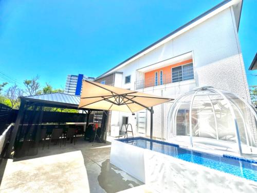 a patio with an umbrella and a swimming pool at バブルハウス付き!白良浜徒歩10分!プール付き!BBQ雨でも可能!貸切!浅築5LDk in Shirahama