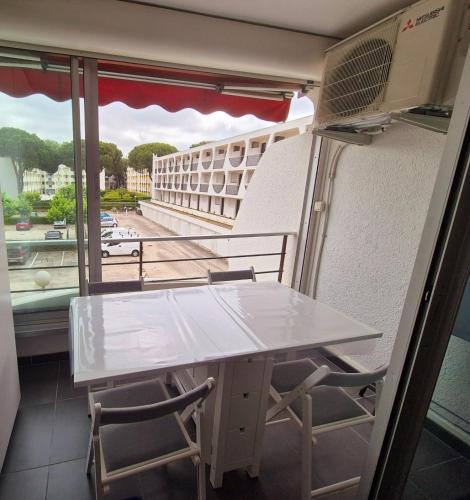 une table blanche et des chaises dans une pièce avec une fenêtre dans l'établissement Studio cosy design au coeur de la ville, à La Grande Motte