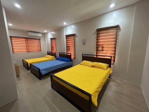 two beds in a room with yellow sheets and windows at 3 Storey Beachfront Villa with Pool by JCV in Nasugbu