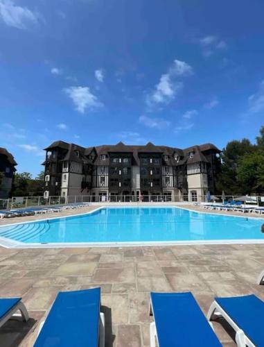 une grande piscine avec des chaises bleues en face d'un bâtiment dans l'établissement Résidence du Golf, à Deauville
