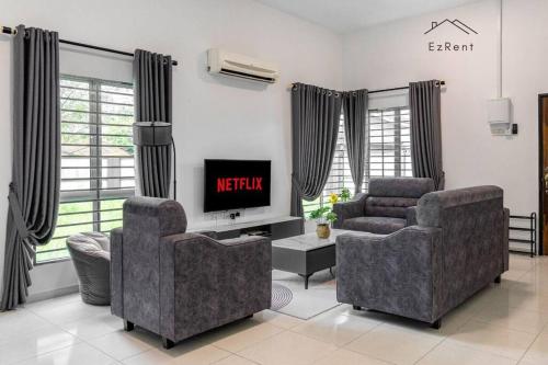 a living room with two chairs and a television at Semi-D Black & White Retreat with Free NetFlix WiFi in Taiping
