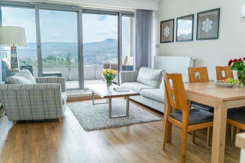 a living room with a table and a couch at Apartview Bukowa II by Rent like home in Wisła