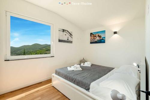 een slaapkamer met een bed en een groot raam bij Reborn House, TerreMarine in La Spezia