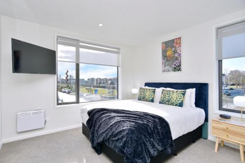 a bedroom with a large bed and two windows at Hereford St Apartment - Christchurch Holiday Homes in Christchurch