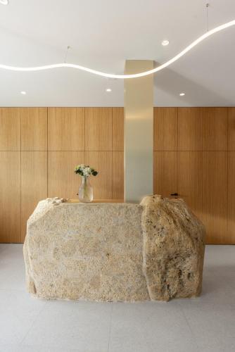 a large rock in a room with a vase with flowers at Hotel Radost in Mikulov