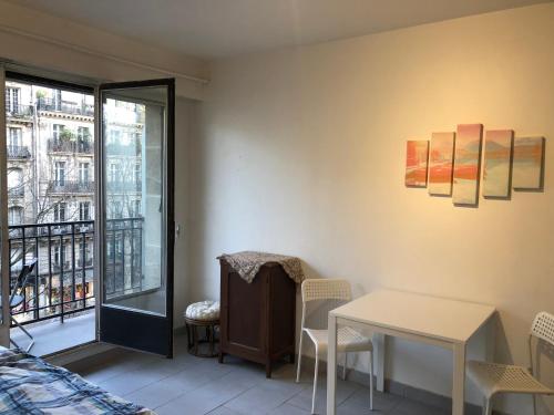 Cette chambre dispose d'une table, de chaises et d'un balcon. dans l'établissement Beautiful studio next to metro, à Paris