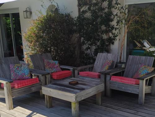 3 chaises en bois et une table sur une terrasse dans l'établissement Maison avec piscine chauffée entre océan et bassin, à Lège-Cap-Ferret
