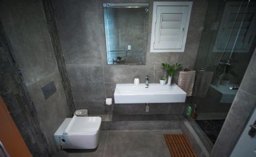 a bathroom with a sink and a toilet and a mirror at 4 Dolphin Views La Mercy Luxury Beachfront Apartment with Private Swimming Pool in La Mercy