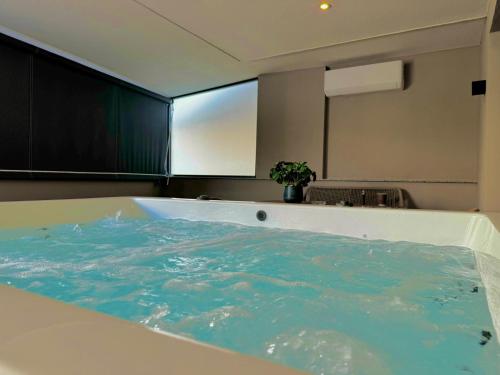 a bath tub filled with blue water in a room at Costa De Luxe Suites in Leptokaria