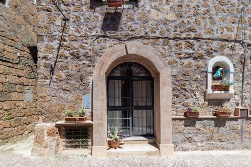 a stone building with a window and potted plants at Radici Etrusche Sutri in Sutri