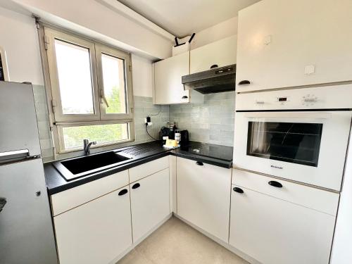 une cuisine avec des armoires blanches, un évier et une fenêtre dans l'établissement Superbe vue - Clim- plage& restaurants 5min à pied, à Antibes