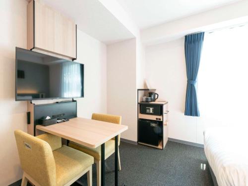 a small room with a table and chairs and a bed at Comfort Hotel Nagoya Meiekiminami in Nagoya