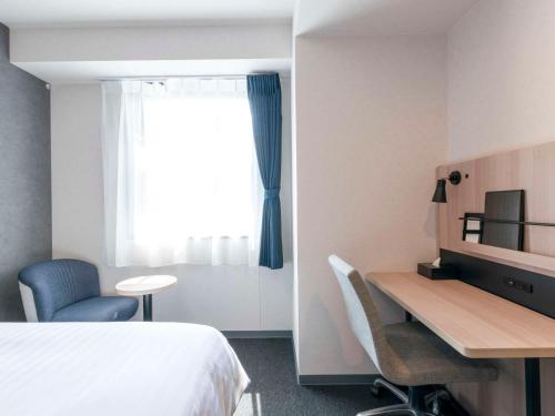 a hotel room with a bed and a desk and a window at Comfort Hotel Nagoya Meiekiminami in Nagoya
