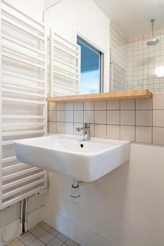 La salle de bains est pourvue d'un lavabo blanc et d'une fenêtre. dans l'établissement 2 bd lovely apt facing Canal St Martin sleeps 6, à Paris