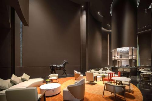 a lobby with a horse statue and tables and chairs at Howard Johnson Royal Hotel Shenzhen in Bao'an