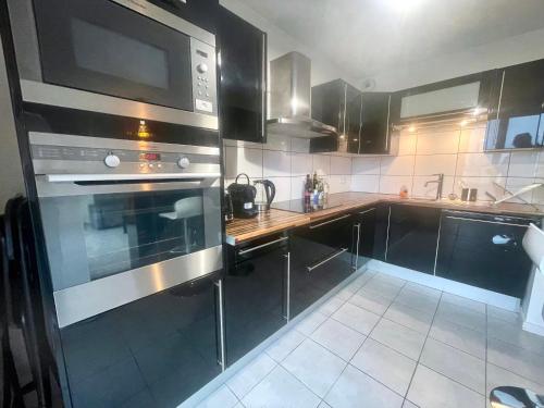 a kitchen with stainless steel appliances and black cabinets at Neyrpic - Cocon douillet -balcon in Rhut