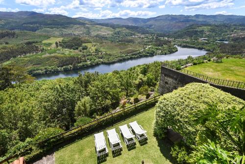 a group of chairs sitting on the grass next to a river at Casas das Olas in Arcos de Valdevez