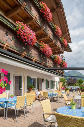 an outdoor patio with tables and chairs and flowers at Hotel Post in Bach