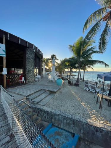 a resort on the beach with chairs and palm trees at Studio 25 m Manganao Joela 4 personnes avec machine a laver in Saint-François