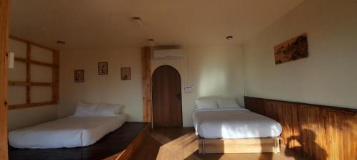 a room with two beds and a door in it at KHIRI HOUSE &Café Farm ดอยช้างเชียงรายที่พักอาข่าเรียวกังสไตล์กลางหมู่บ้านดอยช้าง in Ban Rong Than