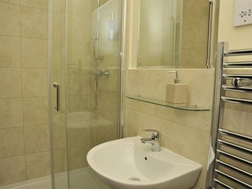 W łazience znajduje się umywalka i prysznic ze szklanymi drzwiami. w obiekcie Hoppers Cottage Guest House w mieście Gateshead