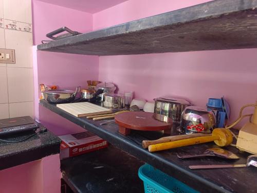 a kitchen with pink walls and a counter with pots and pans at COIMBATORE 2BHK AC Private Villa By Shivalaya -Kovaipudur- in Coimbatore
