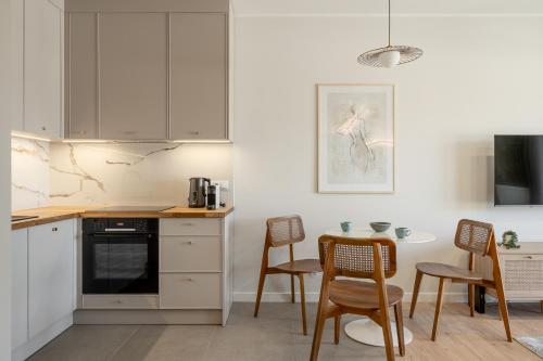 a kitchen with white cabinets and a table and chairs at RentPlanet - Kępa Mieszczańska in Wrocław