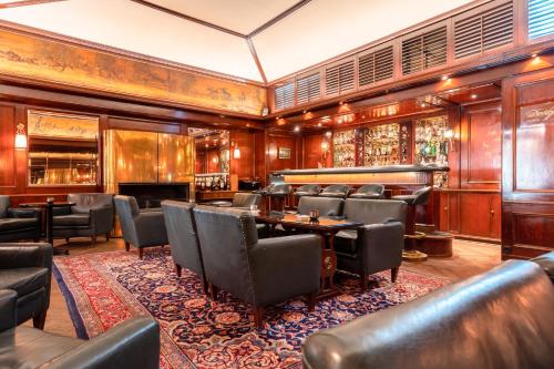 a restaurant with leather chairs and tables and a bar at Hotel Erbprinz - Gourmet & Spa in Ettlingen