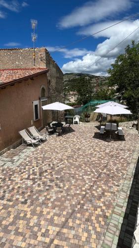 a patio with umbrellas and tables and chairs at da sciuri case vacanza Barisciano in Barisciano