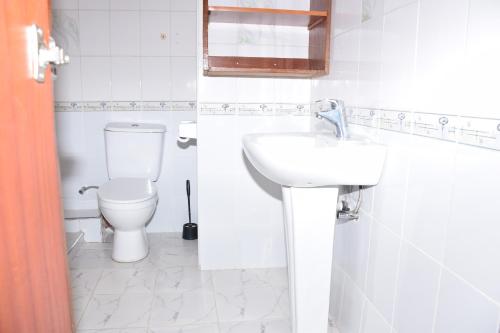 a white bathroom with a toilet and a sink at Zarita Boutique Hotel in Nairobi