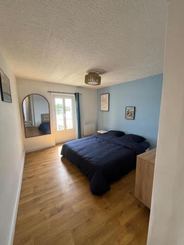 une chambre avec un lit bleu et un miroir dans l'établissement L'escapade de la Pointe, à Bouchemaine