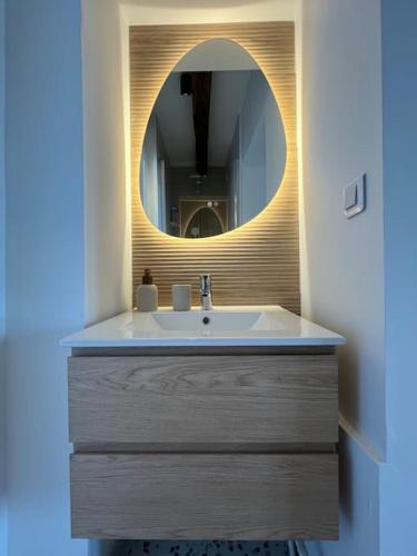 une salle de bain avec un lavabo et un miroir dans l'établissement L'escapade de la Pointe, à Bouchemaine